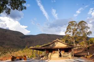 a building with a bench and mountains in the background at Carcará Vacation Homes in Brumadinho