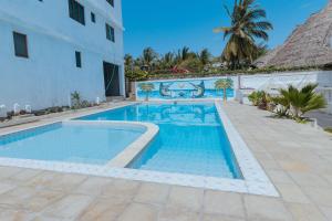a swimming pool in front of a building at Stylish Studio, Pool and Walk to Beach in Watamu