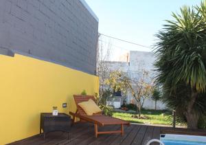 a wooden bench sitting on a deck next to a yellow wall at Memórias in Nogueira da Regedoura