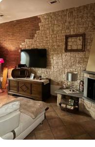 - un salon avec un mur en briques et une télévision dans l'établissement Casa Lucy, à Ponte Buggianese