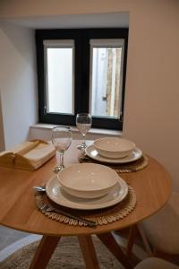 una mesa de madera con dos platos y copas de vino. en VIELA Guest House T1, en Barcelos