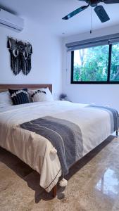 a bedroom with a large bed with a ceiling fan at Town Center Zama Luxury Condo Hotel By Marea in Tulum