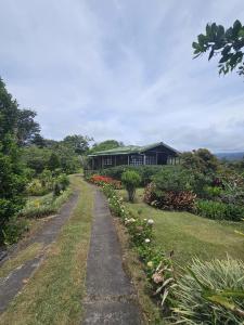 a path leading to a black building with flowers at Mil Flores San Rafael in Turrialba