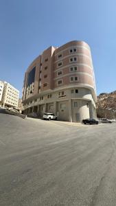 Un gran edificio con coches aparcados delante. en Lualuat Ajyad Hotel, en La Meca