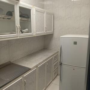 Una cocina con gabinetes blancos y un refrigerador blanco. en فخامة مسرة لشقق المخدومة, en Taif