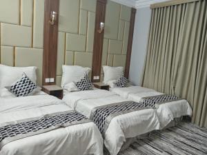 Tres camas en una habitación de hotel con almohadas sobre ellas. en فخامة مسرة لشقق المخدومة, en Taif