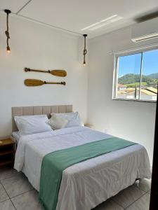 ein weißes Schlafzimmer mit einem großen Bett und einem Fenster in der Unterkunft Lindo apartamento! 2 quartos com suíte, churrasqueira, garagem in Florianópolis