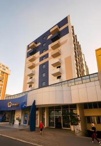 due persone che camminano davanti a un edificio di Atalaia Palace Hotel a Guarapuava