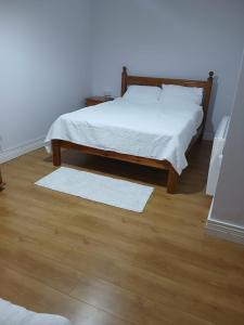 1 dormitorio con 1 cama con sábanas blancas y suelo de madera en A1 apartment, en Loughrea