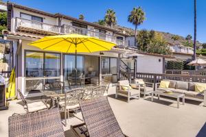 een patio met stoelen en een gele parasol bij Steps to Sand and Surf! Snowbird Haven in Malibu in Solromar