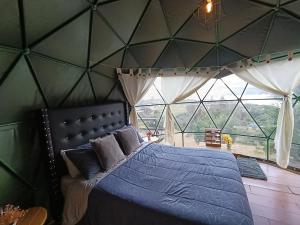 a bedroom with a blue bed with a large window at Glamping El Refugio in Guatavita