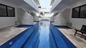 a swimming pool with blue water in a building at Town Center Zama Luxury Condo Hotel By Marea in Tulum