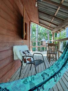 a hammock on a porch with a chair and a table at Cabana Beija Flor, a nest in nature in Tijucas
