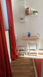 a table and chairs in a room with a red curtain at L'Escale Songeonnaise in Songeons