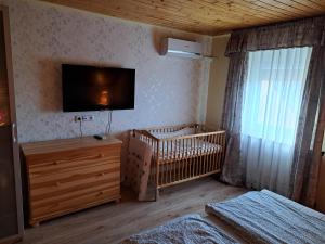 a bedroom with a crib and a tv on the wall at Borostyán Nyaralóház Balatonboglár in Balatonboglár +29 photos