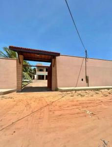 a building with a gate and a dirt road at Casa em porto da dunas in Aquiraz
