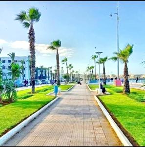 a walkway with palm trees in a park at Apprt Ennakhil 1 in El Jadida +32 photos