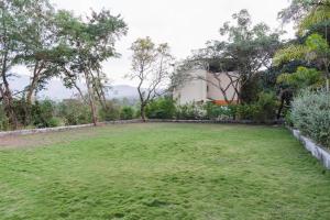 um grande quintal relvado em frente a um edifício em Hotel O The Nature World Resort em Kharakvasla