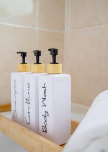 Un par de dispensadores de jabón blanco sobre un estante. en Stylish central location 3 bedroom house, en Ely