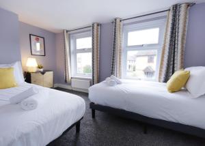 Dos camas en una habitación con dos ventanas. en Stylish central location 3 bedroom house, en Ely