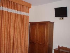 Habitación con cortina, TV y armario. en Hotel Pattaya, en Mocejón