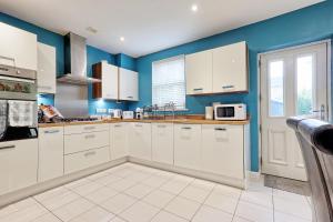 a kitchen with white cabinets and blue walls at Spacious 4BR Townhouse, Sleeps 9, Fast WIFI, FREE PARKING, Contractor friendly in Colchester