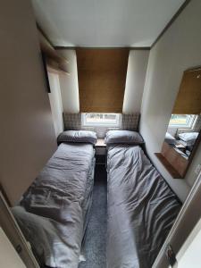 een kleine kamer met twee bedden en een spiegel bij Flamingo land holiday home in Kirby Misperton