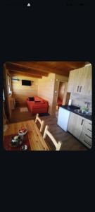 a living room with a red couch and a kitchen at Fruškogorske brvnare in Sremski Karlovci