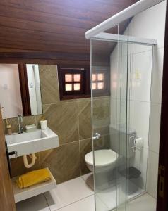 a bathroom with a toilet and a glass shower at Chalé aconchegante in Gravatá