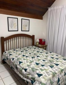 a bedroom with a bed with a quilt on it at Chalé aconchegante in Gravatá