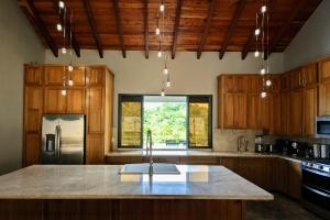 a kitchen with wooden cabinets and a large island at Cayo Casa Grande Modular Villa with Pool, Gym & Valley Views in Santa Elena