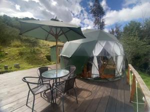 a table and chairs and a tent on a deck at Glamping El Refugio in Guatavita