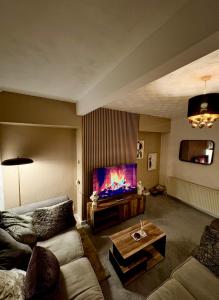 a living room with a couch and a flat screen tv at Cozy corner-Sleeps 8 guest Entire house Glasgow very central in Glasgow