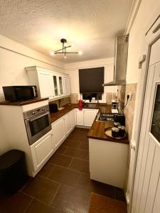 a kitchen with white cabinets and a stove top oven at Cozy corner-Sleeps 8 guest Entire house Glasgow very central in Glasgow