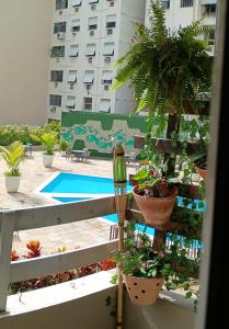 a balcony with potted plants and a swimming pool at Apart Novidade do verao in Rio de Janeiro