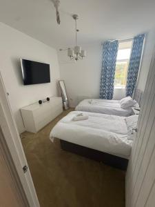 a bedroom with two beds and a tv and a window at Pentwyn avenue apartment in Mountain Ash