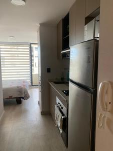 a kitchen with a stainless steel refrigerator and a bedroom at Departamento estudio sector casino dreams temuco in Temuco