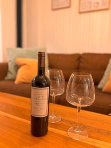 Una botella de vino y dos copas de vino en una mesa en Pirca NQN, en Neuquén