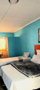 two beds in a room with a blue wall at Platinum Palace Guest House in Rustenburg