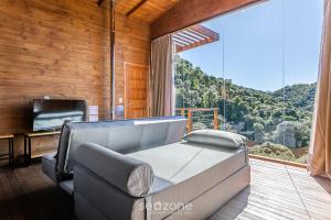 a living room with a couch and a large window at Cabana com vista Serra Catarinense VST023 in São Paulo dos Pinhais