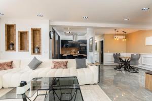 a living room with a white couch and a kitchen at Appartement avec salle de cinema in Agadir