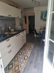 eine Küche mit weißen Schränken und einem Fliesenboden in der Unterkunft Appartamento vicino al mare in Castiglioncello + 4 Fotos