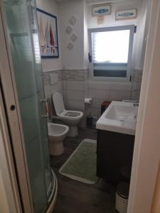 ein Badezimmer mit Waschbecken und Toilette und einem Fenster in der Unterkunft Appartamento vicino al mare in Castiglioncello