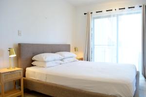 ein Schlafzimmer mit einem großen weißen Bett mit einem Fenster in der Unterkunft Beachfront 3-Bed with Pool & Stunning Ocean Views in Trinity Beach