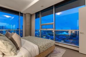 a bedroom with a bed and large windows at 2 Storey Penthouse Panoramic Views Parking Stampede in Calgary