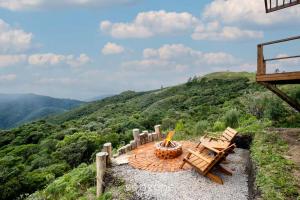 un patio avec deux chaises et un foyer sur une colline dans l'établissement Cabana incrível p/ casais na região serrana VST011, à São Paulo dos Pinhais