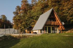 a house with a gambrel roof on top of a yard at Vikendica Buzadzija M&N in Piskavica