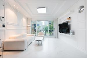 a white living room with white furniture and a tv at Domostay in Seogwipo