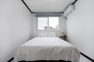 a bedroom with a white bed and a window at Domostay in Seogwipo