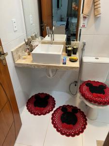 a bathroom with a sink and red and black mats on the floor at Casa com suite bem localizada in Manaus